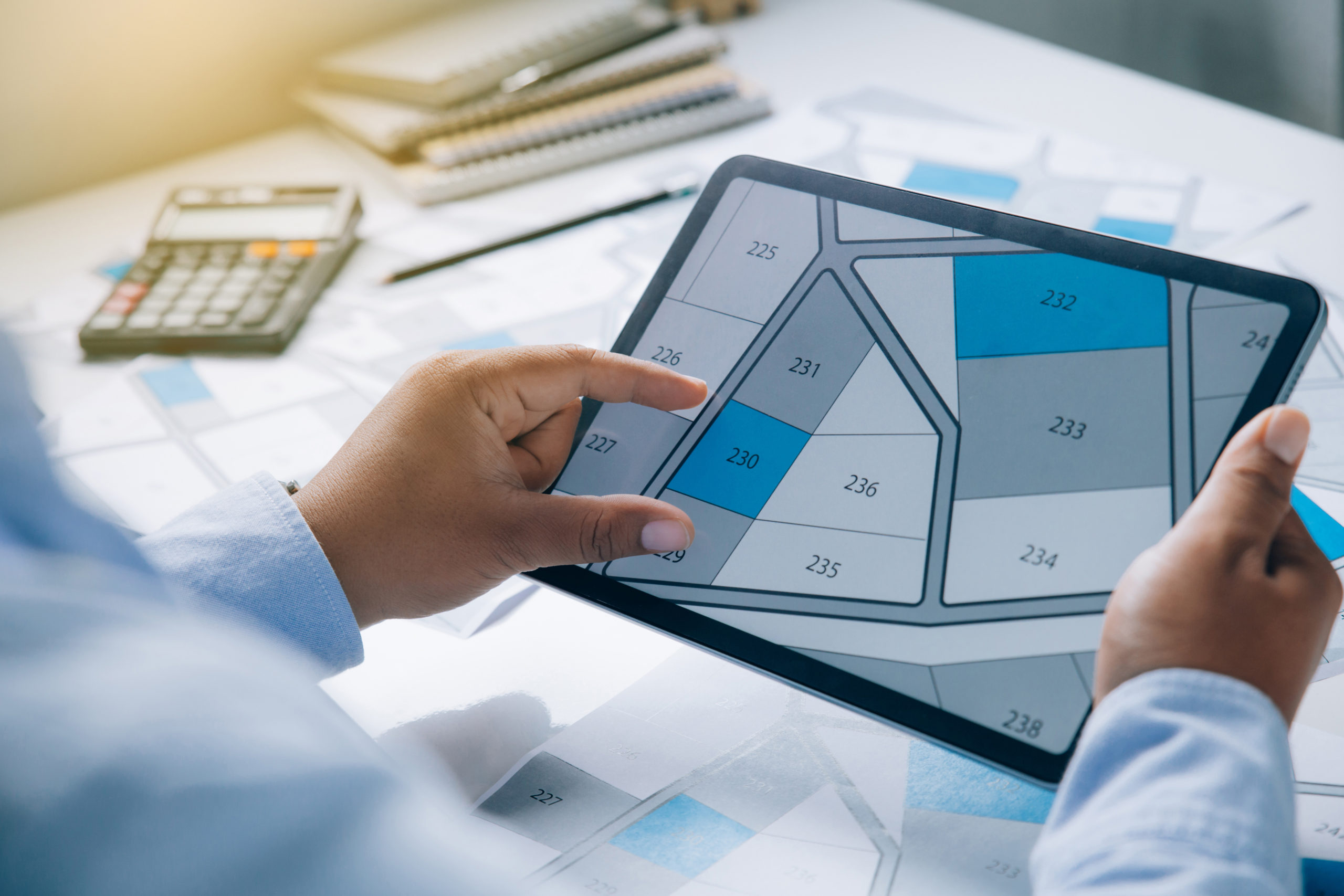 Person holding a tablet looking at lots of lands. Property management. The Importance of Finding the Right Commercial Property Management Service.